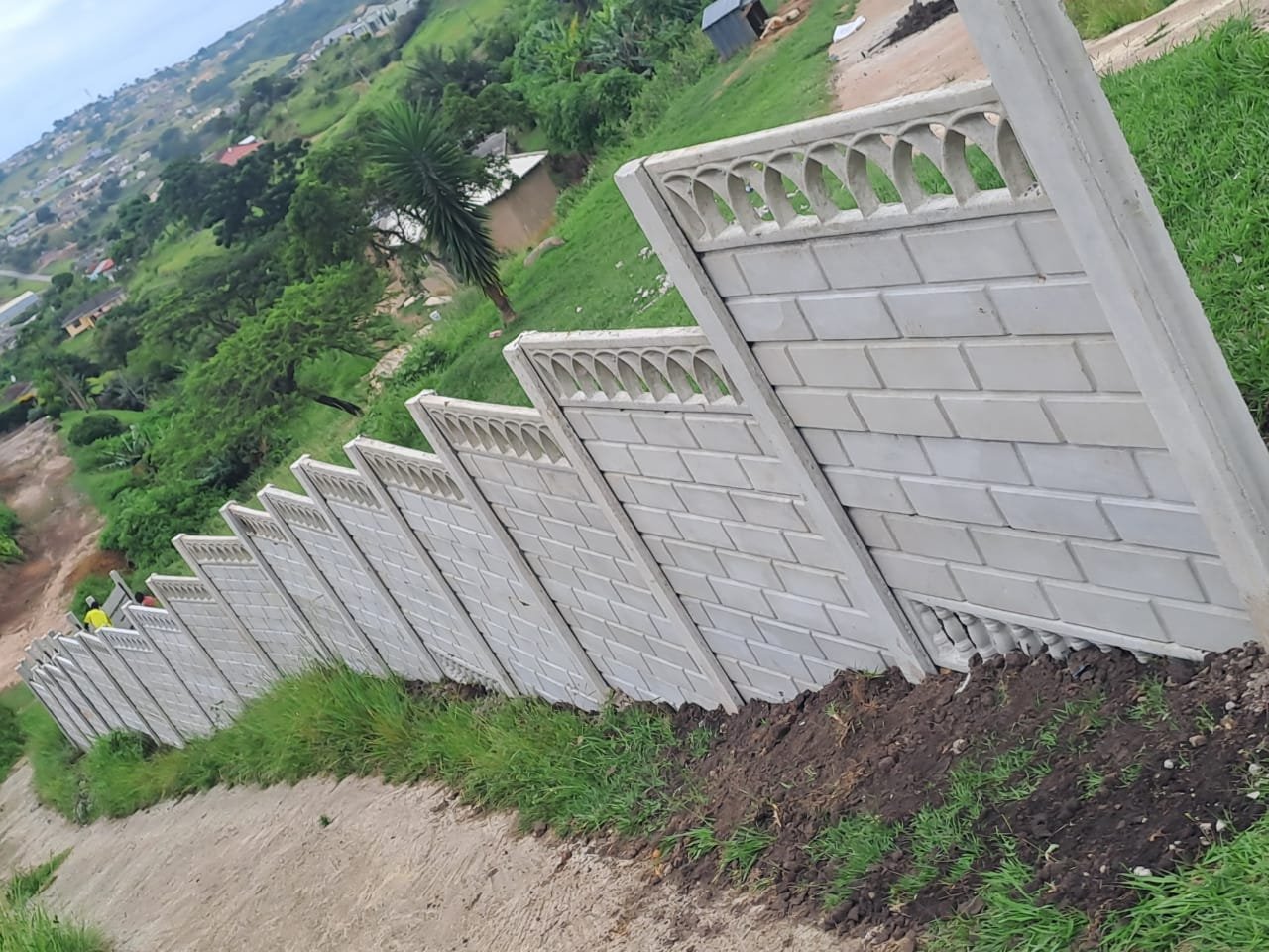 Decorative precast boundary wall with arched cornice detail, installed along a sloped KwaZulu-Natal site