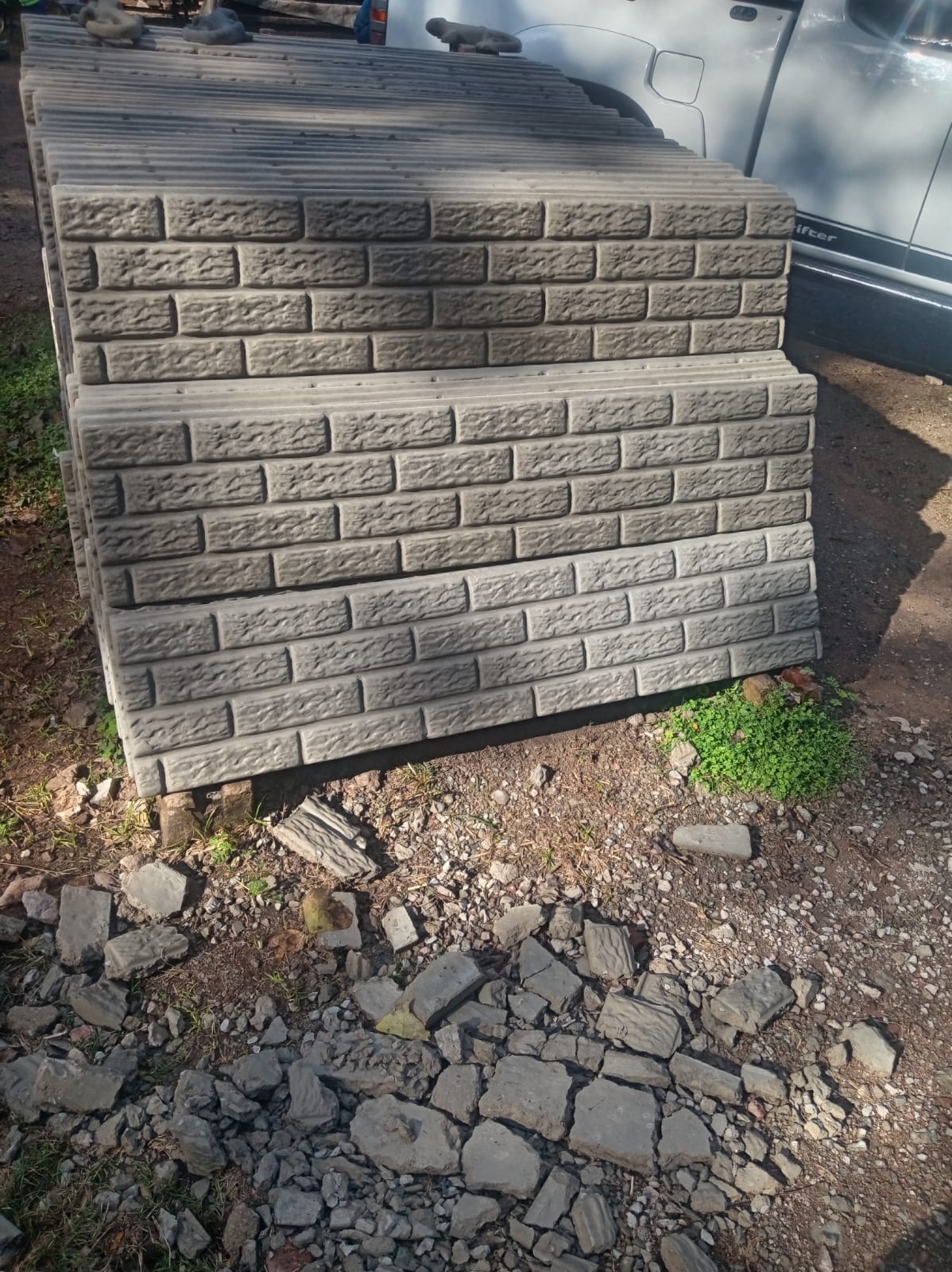 Stacked brick-pattern precast fence panels ready for delivery