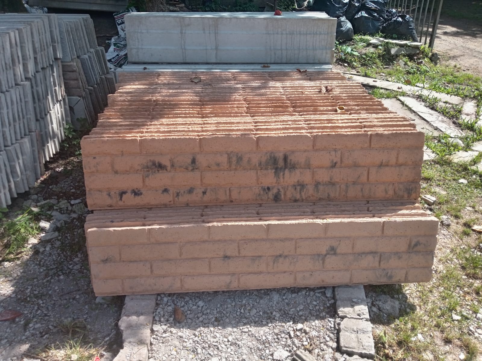 Red brick-finish precast fence panels stacked in the yard
